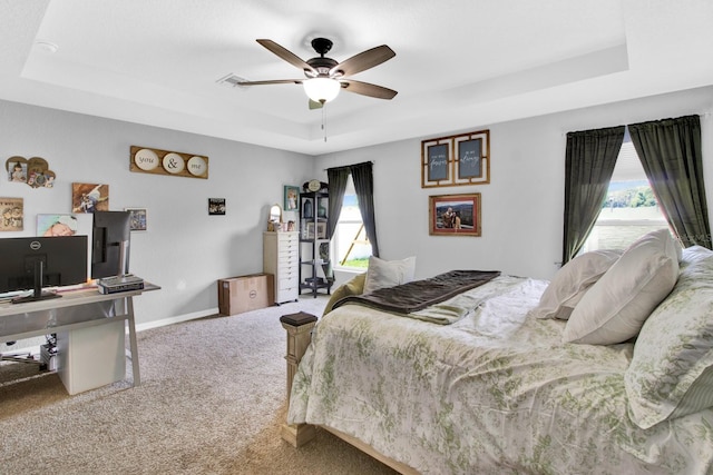 bedroom featuring ceiling fan, carpet flooring, and a tray ceiling