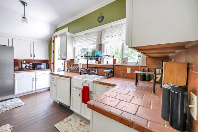 kitchen featuring wood-type flooring, stainless steel refrigerator, tile countertops, crown molding, and white cabinets