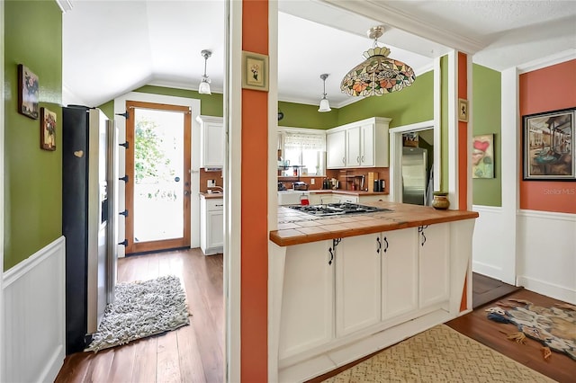 kitchen featuring light hardwood / wood-style flooring, hanging light fixtures, white cabinetry, tile countertops, and stainless steel appliances