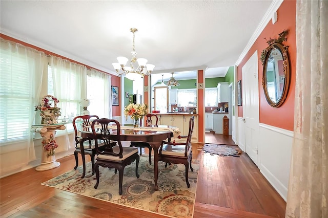 dining area featuring hardwood / wood-style floors, ornamental molding, and a chandelier