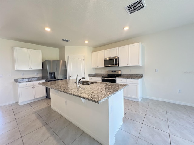 kitchen with an island with sink, sink, stainless steel appliances, and light tile patterned floors