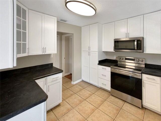 kitchen featuring light tile patterned flooring, white cabinets, and stainless steel appliances