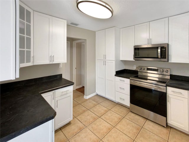 kitchen with stainless steel appliances, white cabinetry, and light tile patterned flooring