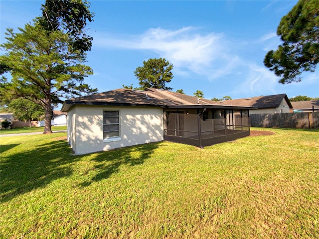 rear view of house featuring a lawn and a sunroom