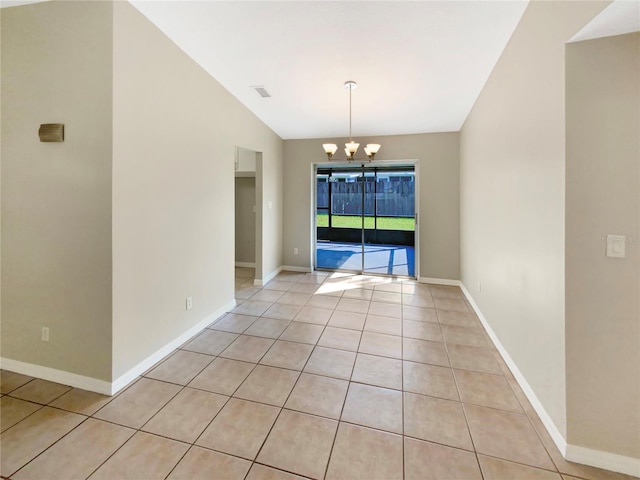 spare room with light tile patterned flooring, vaulted ceiling, and an inviting chandelier