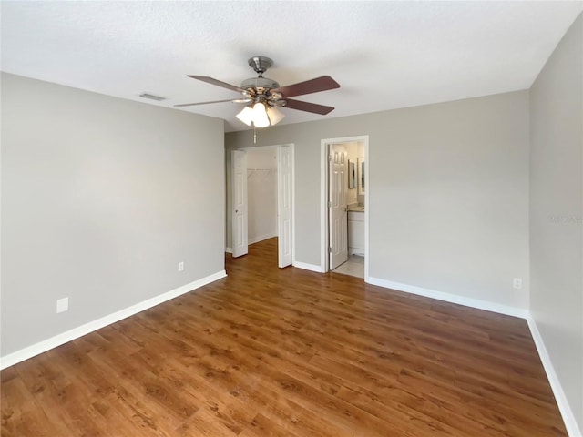 unfurnished bedroom featuring ensuite bathroom, wood-type flooring, a closet, and ceiling fan