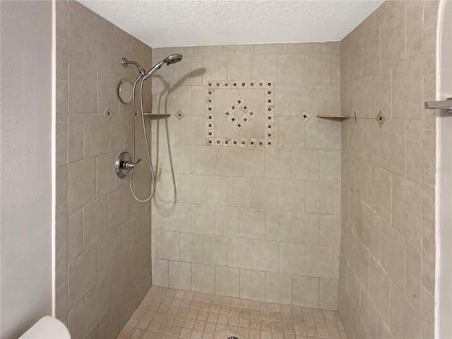 bathroom with a textured ceiling and tiled shower