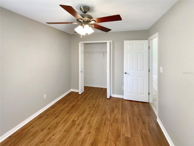 unfurnished bedroom featuring ceiling fan, hardwood / wood-style flooring, and a closet