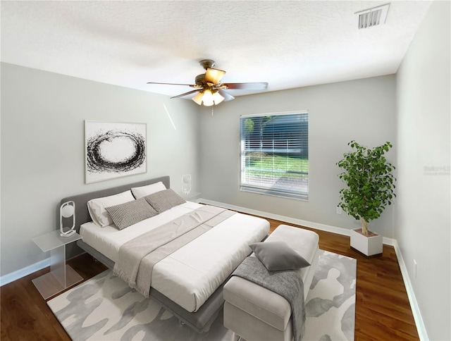 bedroom with ceiling fan, hardwood / wood-style flooring, and a textured ceiling