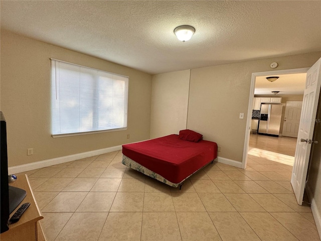 tiled bedroom with stainless steel refrigerator with ice dispenser and a textured ceiling