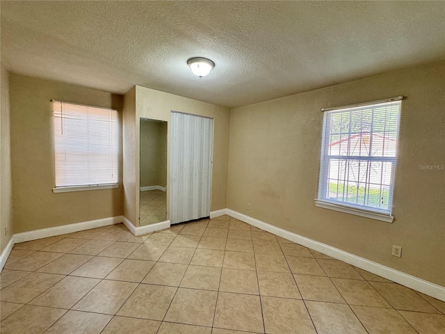 unfurnished bedroom with a textured ceiling and light tile patterned floors