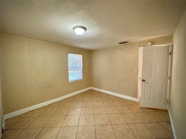 unfurnished room featuring light tile patterned floors and a textured ceiling