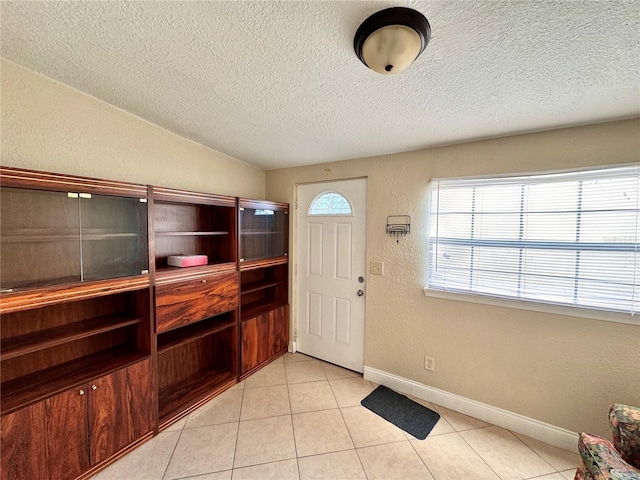 tiled entrance foyer with vaulted ceiling and a textured ceiling