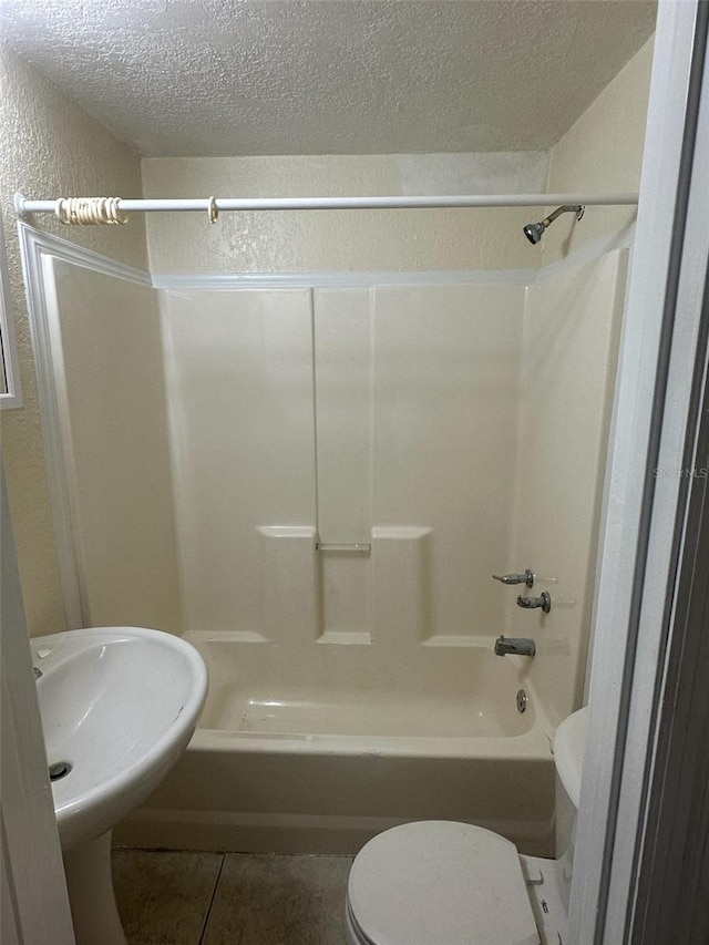 full bathroom featuring a textured ceiling, toilet, sink, shower / tub combination, and tile patterned floors