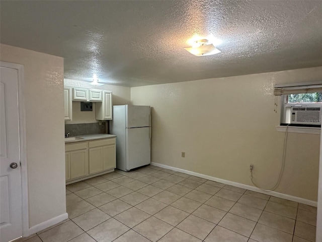 kitchen with light tile patterned floors, sink, a textured ceiling, and white fridge