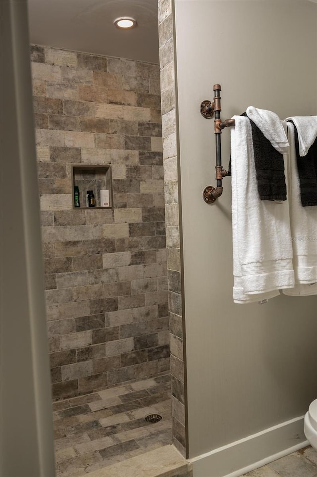 bathroom featuring tiled shower, toilet, and tile patterned floors