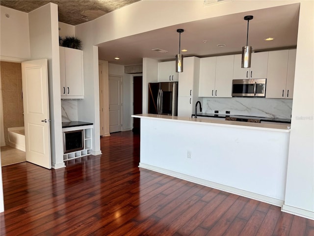 kitchen featuring white cabinets, pendant lighting, stainless steel appliances, and dark hardwood / wood-style floors