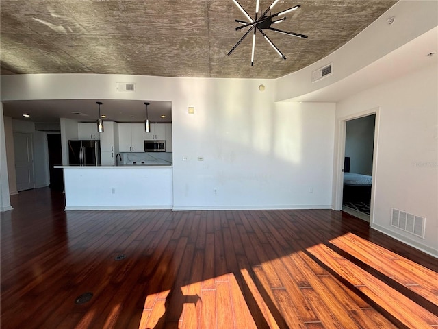 unfurnished living room with a chandelier, dark hardwood / wood-style flooring, and sink