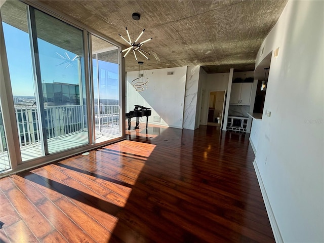 unfurnished room with a notable chandelier, expansive windows, and dark wood-type flooring