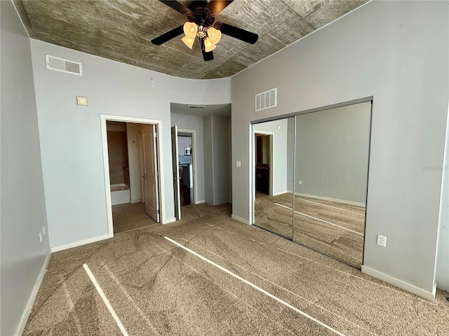 unfurnished bedroom with carpet flooring, ensuite bath, ceiling fan, and a closet