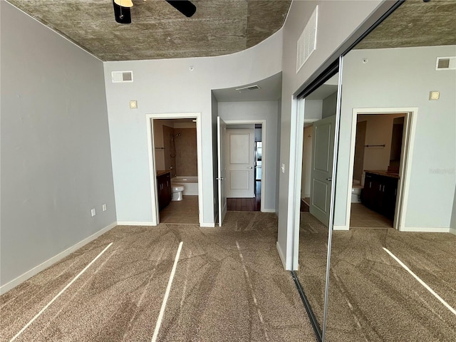 unfurnished bedroom featuring carpet flooring, ensuite bathroom, ceiling fan, and a closet