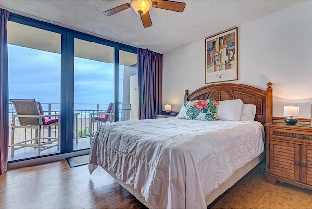 bedroom with a ceiling fan, wood finished floors, floor to ceiling windows, a textured ceiling, and access to outside