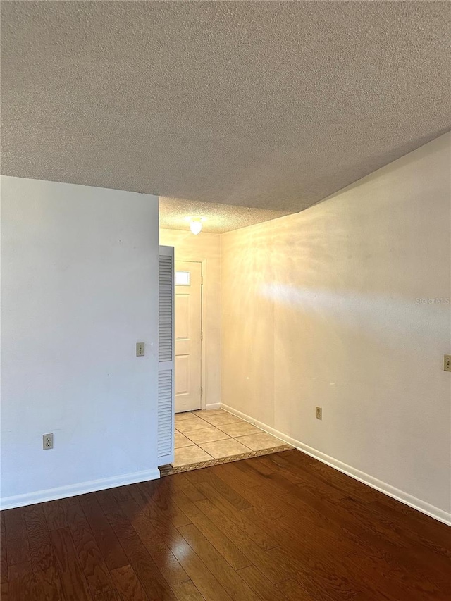 unfurnished room featuring light wood-style flooring, baseboards, and a textured ceiling