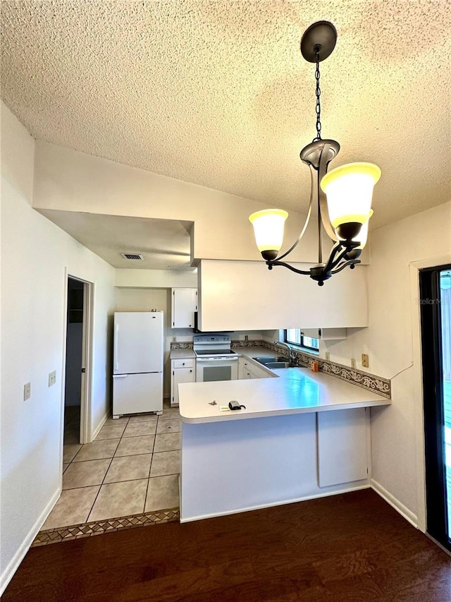 kitchen with white appliances, white cabinets, decorative light fixtures, a peninsula, and light countertops