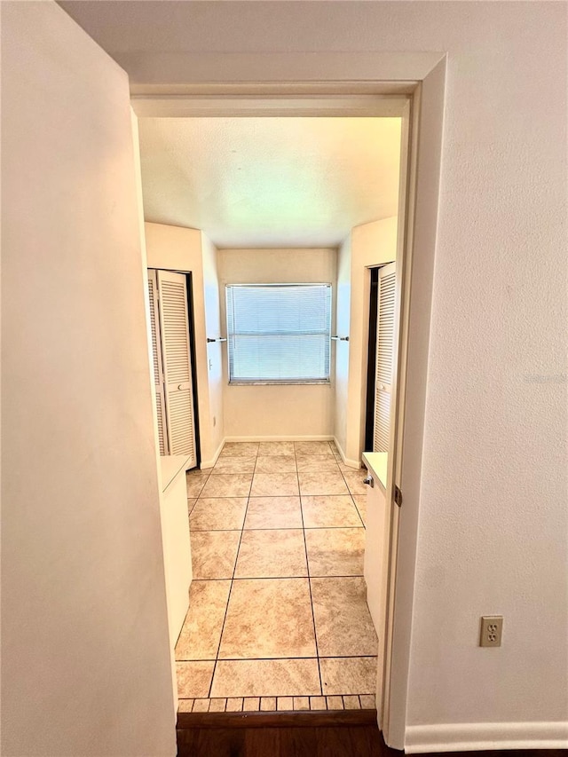 hallway with light tile patterned flooring and baseboards