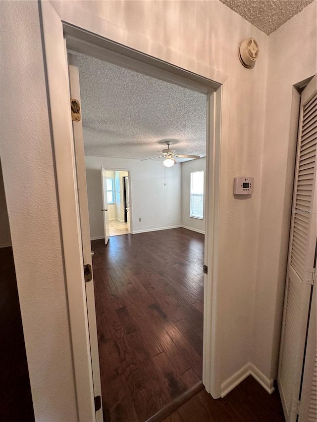 hall with dark wood-type flooring and a textured ceiling