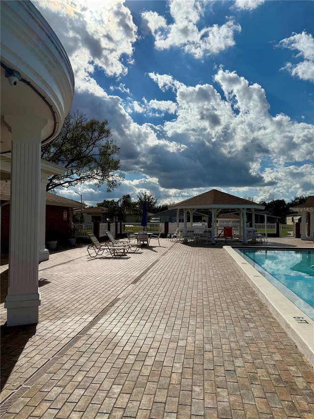 pool with a patio area, fence, and a gazebo