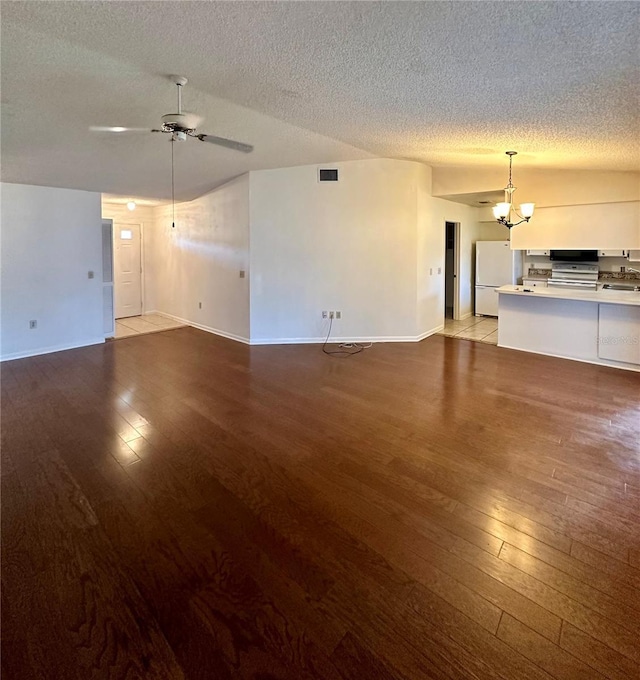 unfurnished living room featuring light wood finished floors, baseboards, visible vents, a textured ceiling, and ceiling fan with notable chandelier