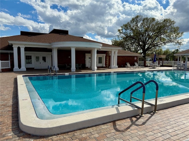 community pool with a patio area and fence