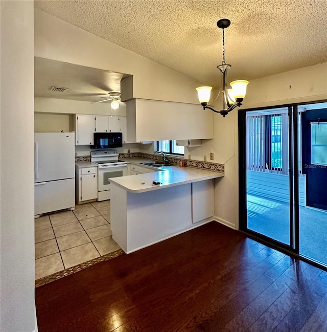 kitchen featuring white appliances, white cabinets, hanging light fixtures, a peninsula, and light countertops