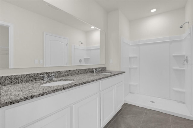 full bathroom with double vanity, tile patterned flooring, a sink, and a shower stall