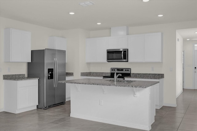 kitchen with visible vents, appliances with stainless steel finishes, white cabinetry, a kitchen island with sink, and dark stone counters