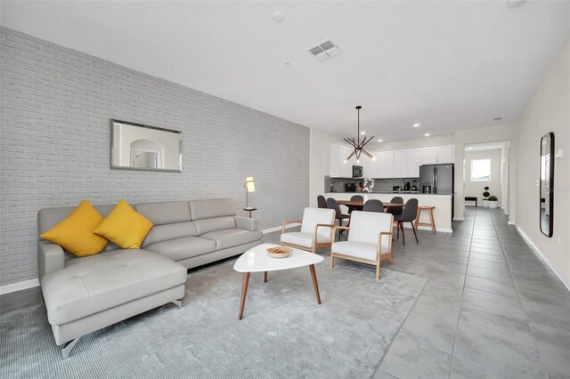 tiled living room with a notable chandelier and brick wall