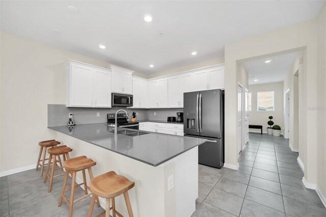 kitchen with light tile patterned flooring, stainless steel appliances, sink, white cabinets, and kitchen peninsula