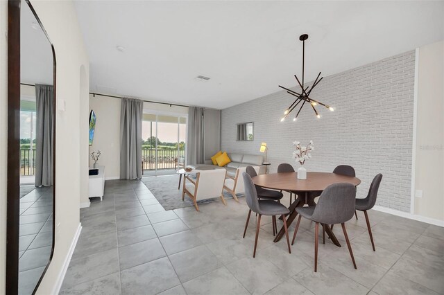 tiled dining area featuring brick wall and a chandelier