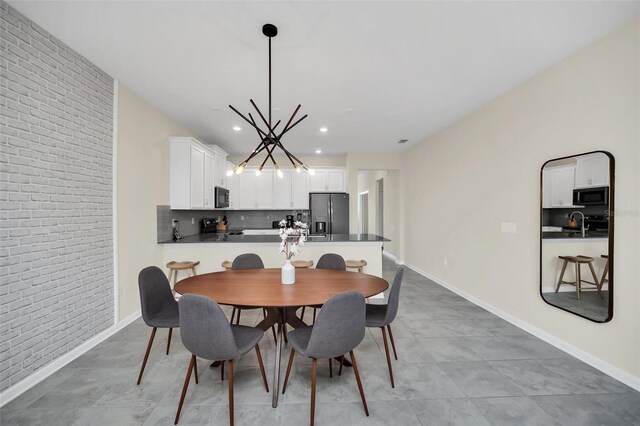 dining room featuring brick wall, tile patterned floors, sink, and a chandelier