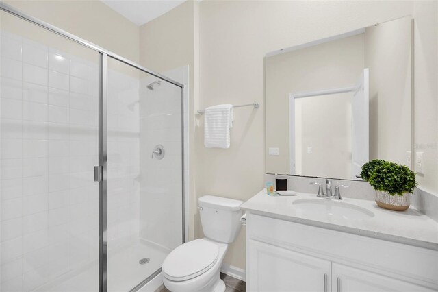 bathroom with toilet, vanity, and a shower with shower door