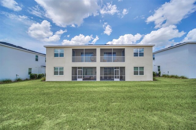 rear view of property with a balcony and a lawn