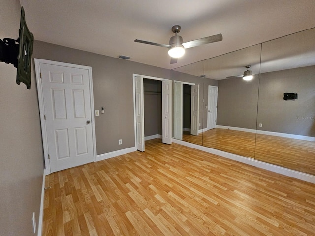 unfurnished bedroom with light wood-type flooring, two closets, and ceiling fan