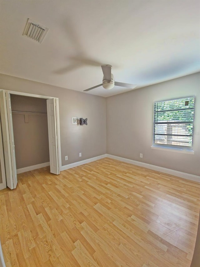 unfurnished bedroom featuring light wood-type flooring, ceiling fan, and a closet