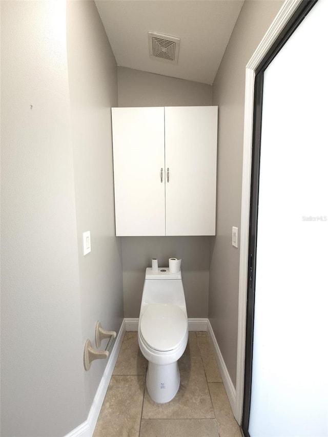 bathroom featuring lofted ceiling, tile patterned flooring, and toilet