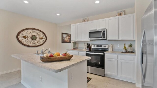 kitchen featuring white cabinets, stainless steel appliances, an island with sink, and light tile patterned flooring