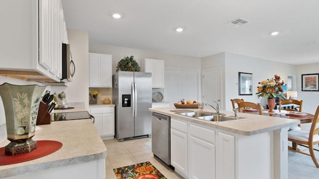 kitchen with a kitchen island with sink, white cabinetry, light tile patterned floors, sink, and appliances with stainless steel finishes