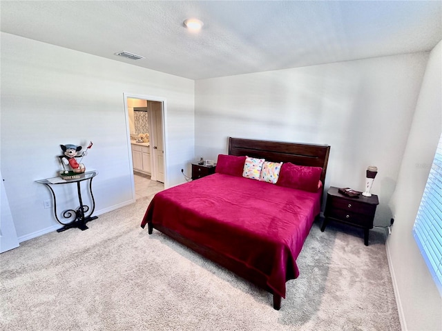 bedroom with light carpet and ensuite bathroom