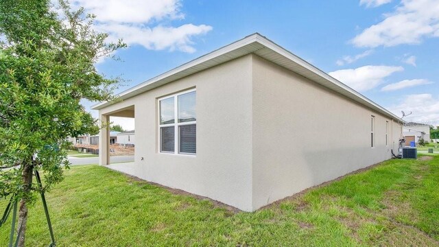 view of side of home featuring a lawn and central AC