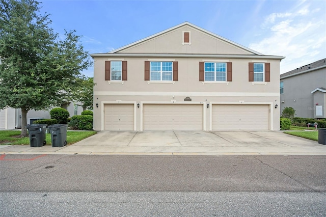 traditional home with driveway, an attached garage, and stucco siding